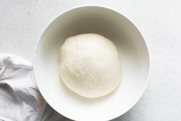 Overhead view of challah dough in a white mixing bowl, top view of homemade challah dough resting in a white mixing bowl, process of making challah