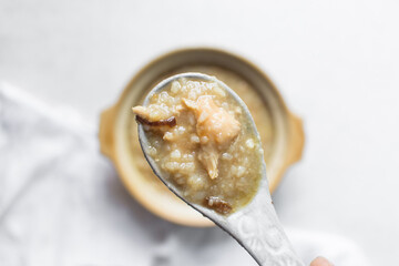 Overhead view of rice chicken congee in a spoon, top view of rice and chicken porridge, chinese...
