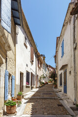 ARLES, FRANCE: Narrow old cobblestone street lined with traditional houses and blue colored shutters