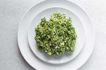 Overhead view of grated okra on a white plate, top view of finely diced okro on a plate 