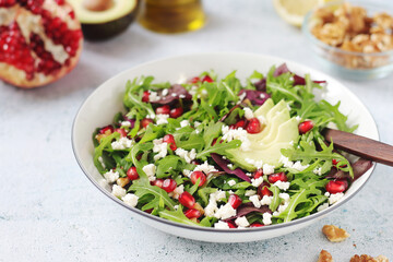 A plate with green rocket salad with pomegranate and avocado
