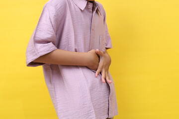 Asian little boy standing while grimacing in pain. He is suffering from stomach ache or diarrhea