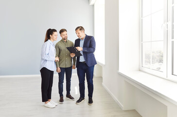 Fototapeta premium Realtor, real estate agent showing offering young couple family property, buying and selling service, helping consultation about mortgage, insurance, rent, tenancy agreement, building contract