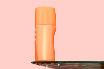 Orange cosmetic plastic container for cream on glass table.