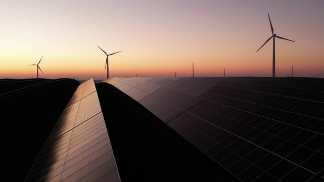 Solar panels park and wind turbines at sunset.Windmill turbines generating green energy electric.Green energy reduce carbon emissions and makes earth cleaner and more ecological.	
