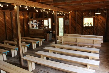 Rustic Wooden Barn Interior with Benches and String Lights for Wedding