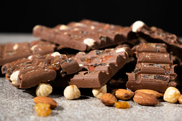 Lots of chocolate bars with nuts and raisins on a black background