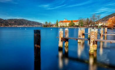 Eine Klosterwirtschaft an einem blauen See, davor ein Bootsteg, blauer Himmel - A monastery inn on a blue lake, in front of it a jetty, blue sky