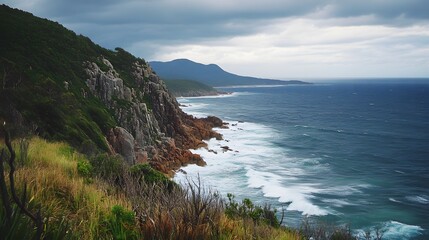 A coastal landscape with rugged cliffs, crashing waves, and wind-swept vegetation.