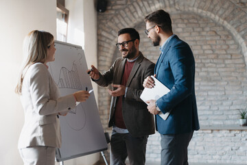 A group of business people are standing in front of a white board