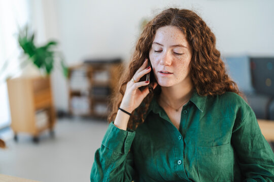 Young woman having a phone conversation in a cozy home office setting