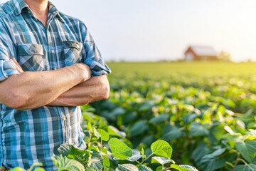 Fototapeta premium A close-up of a farmer standing confidently in a field of crops with arms crossed, wearing a checkered shirt. 