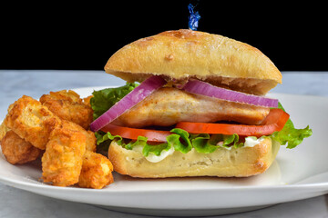 chicken sandwich  with a side of tater tots