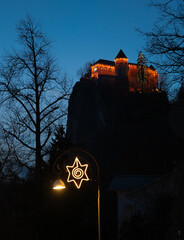 Weihnachten in Bled: angestrahlte Burg Bled und Weihnachtsschmuck der Promenade im Vordergrund