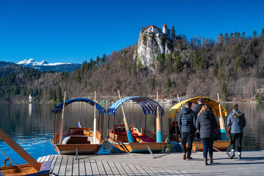 Touristen und Ausflugsboote auf dem See in Bled, im Hintergrund Burg Bled und die Alpen, Slowenien