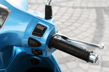 Motorbike throttle of a blue scooter on a cobblestone street. Urban transport concept for city...