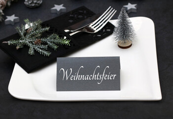 Gedeckter Tisch mit Teller,  Besteck, und einer Tischkarte mit der Beschriftung Weihnachtsfeier .