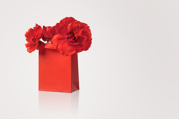 Red shopping and gift bag with red tulip flowers. Concept Valentine's day, gift package and delivery. Sale, shopping, promotion, pleasant surprises, black friday