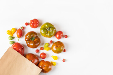 Red, green, yellow and striped tomatoes in paper bag. Flat lay. Healthy food, fresh healthy vegetables from the garden