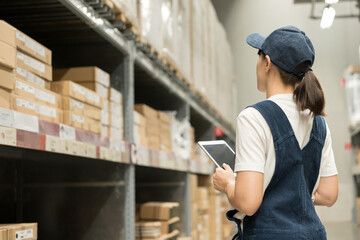 Warehouse worker hands holding tablet check stock on tall shelves in warehouse storage. Asian woman auditor or staff work looking up stock taking inventory in cargo store. Logistic business work.