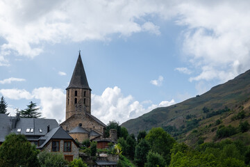 Front view of the town of Unha from the old road. A small town at the foot of the Pyrenees mountains near Baqueira. The day is cloudy and gray with a threatening sky and a magical atmosphere