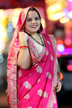 A radiant smile and colorful traditional dress light up the night cityscape. A beautiful blend of culture and modern city glow.
