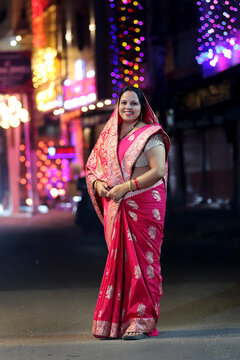 A radiant smile and colorful traditional dress light up the night cityscape. A beautiful blend of culture and modern city glow.