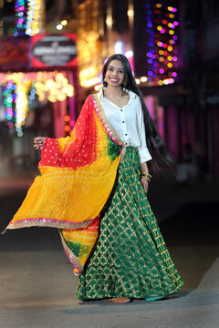 A radiant smile and colorful traditional dress light up the night cityscape. A beautiful blend of culture and modern city glow.