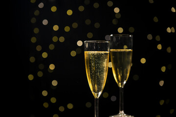 Two glasses of bubbling champagne with golden Christmas lights in the background, close up shot. Celebration, joyful, and happy event concept.