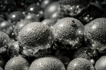 Festive decoration, snow falling on Christmas silver baubles with blurred discrete golden lights in the background, close up shot.