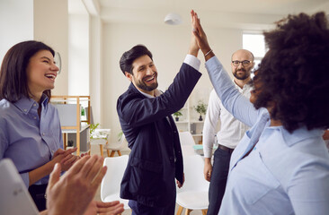 Happy office fun, overjoyed multiethnic businesspeople giving high five, engaged in teambuilding...