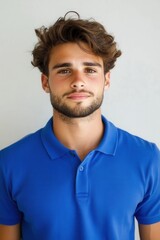 Fototapeta premium Portrait of a young man with curly hair and a beard wearing a blue polo shirt