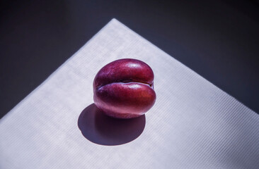 A plum on a windowsill, illuminated by a sunbeam. It looks like a woman's lips.