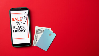 Top view of a smartphone screen displaying a Black Friday online sale on red background with credit cards and money