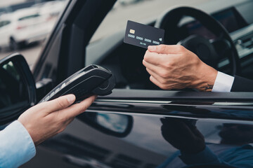 Businessman in suit using contactless payment from car in city parking lot