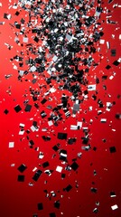 Shimmering silver and black confetti cascading against a vibrant red backdrop in festive celebration