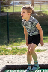 Joyful emotion of little boy jumping on outdoor playground trampoline