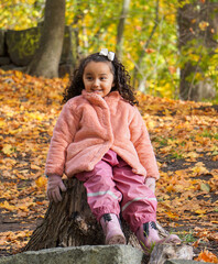 A young girl sitting on a tree stump