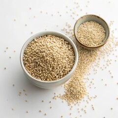 A white bowl filled with uncooked quinoa sits next to a smaller bowl of the same grain on a white background. The quinoa represents a healthy and nutritious food choice for any diet.