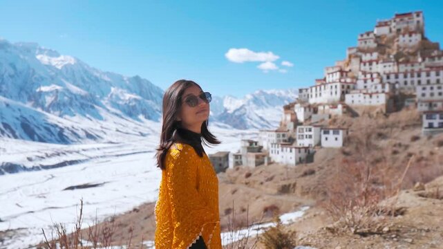 Portrait of young Indian woman standing against key monastery and Snow covered Himalaya mountains during winter season at Spiti Valley, India. Winter travel, Exploring remote places. 