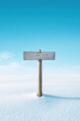 Naklejka premium Wooden sign post in snowy landscape against clear blue sky