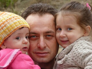 Fatherhood in Full Embrace: A Warm Moment of a Father Holding His Two Daughters, Symbolizing...