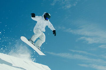 an energetic snowboarder mid-jump against a bright winter sky