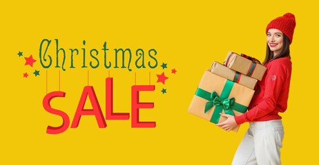 Beautiful young woman holding gift boxes on yellow background. Banner for Christmas sale