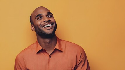 Obraz premium Smiling young Black man against a vibrant orange background.
