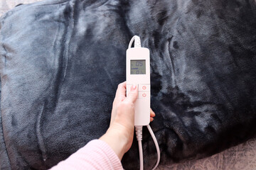Electric blanket. Woman holding controller of electric blanket.  © Alina_Stor