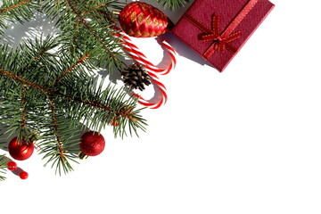 On a white isolated background there are Christmas tree decorations and fir branches.	