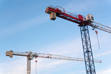 A pair of tower cranes rises into the sky, adding an urban accent against the clear blue...