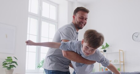 Happy loving family father and son having fun together during leisure, playing flying plane. Joyful young man lifting excited laughing little boy, holding child while kid putting up arms like plane.