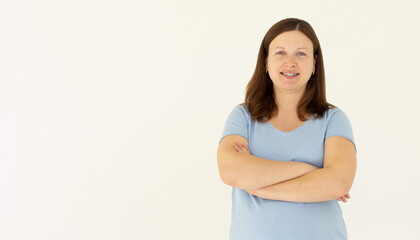 Image of cheerful woman in basic t-shirt smiling at camera while standing with arms crossed isolated over white background